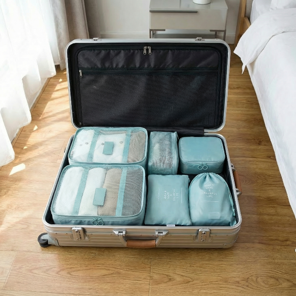 AïtaVia set of 7 teal luggage organizers in a silver suitcase, including mesh cubes and zippered pouches.