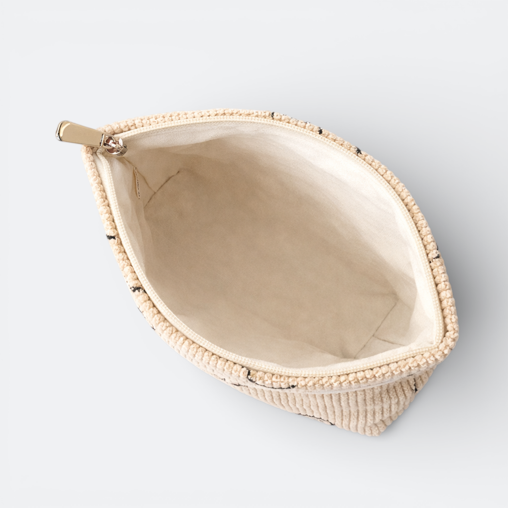 AïtaVia beige corduroy travel toiletry bag with black embroidered details and a gold zipper.