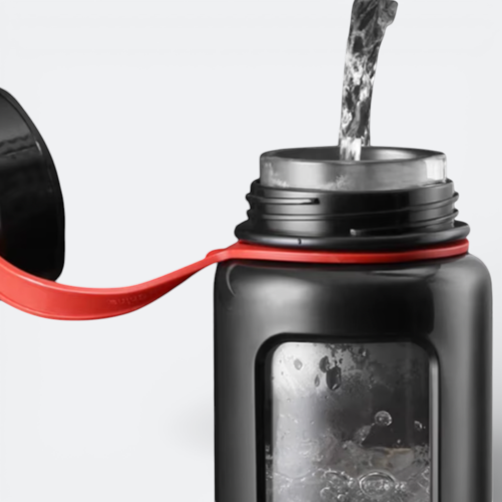AïtaVia black glass water bottle with red strap, being filled with water.