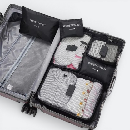 AïtaVia black nylon travel packing cubes and secret pouches neatly organized inside a suitcase.
