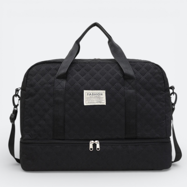 AïtaVia black quilted travel duffel bag with two top handles and a detachable shoulder strap, featuring a separate zippered compartment at the bottom.