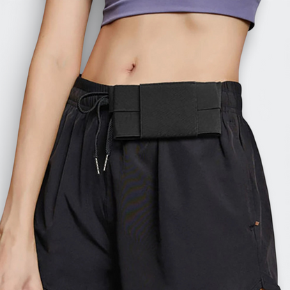 AïtaVia black secure travel belt pouch with elastic strap, worn discreetly under shorts.