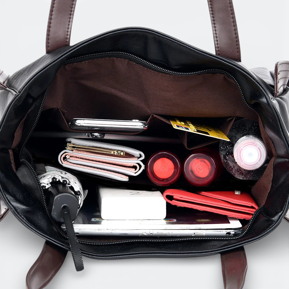 AïtaVia black soft leather tote bag interior with organized essentials: phone, wallet, makeup, water bottle, and umbrella.