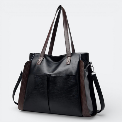 AïtaVia black soft leather tote bag with brown accents and two front pockets, featuring shoulder straps and a detachable crossbody strap.