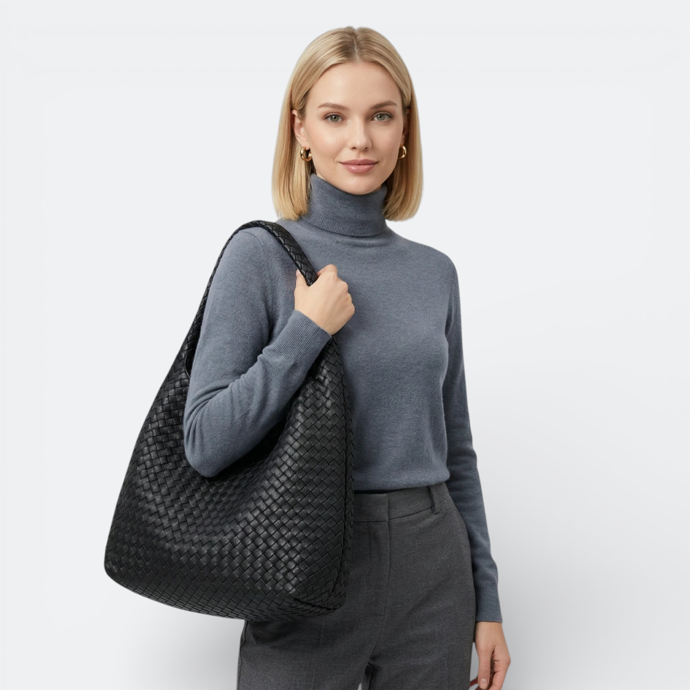 AïtaVia black woven leather hobo handbag with braided strap, worn by a woman in a grey turtleneck and trousers.