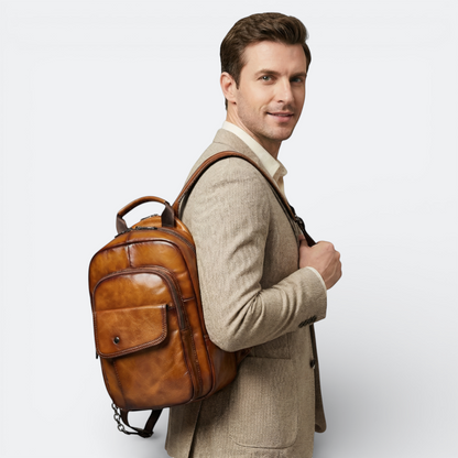 AïtaVia men's genuine leather backpack in rich brown, featuring multiple pockets and a classic design, worn with a beige blazer.