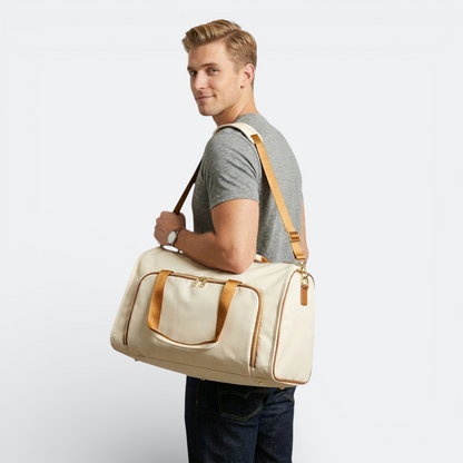 AïtaVia convertible duffel bag in cream canvas with tan leather trim and straps, worn crossbody by a man.