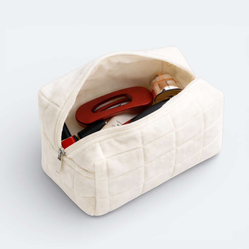 AïtaVia cream plush quilted makeup bag with zipper, holding lipstick, a red hair clip, and a compact.