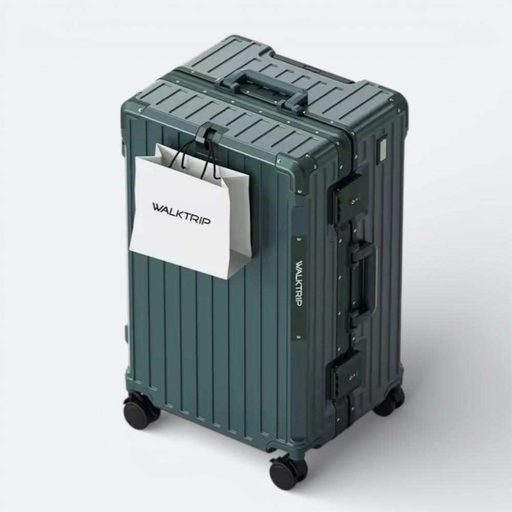 AïtaVia dark green hardshell suitcase with spinner wheels and TSA locks. Features a ribbed texture and a white shopping bag hanging from the handle.