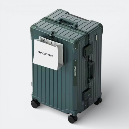 AïtaVia dark green hardshell suitcase with spinner wheels and TSA locks. Features a ribbed texture and a white shopping bag hanging from the handle.