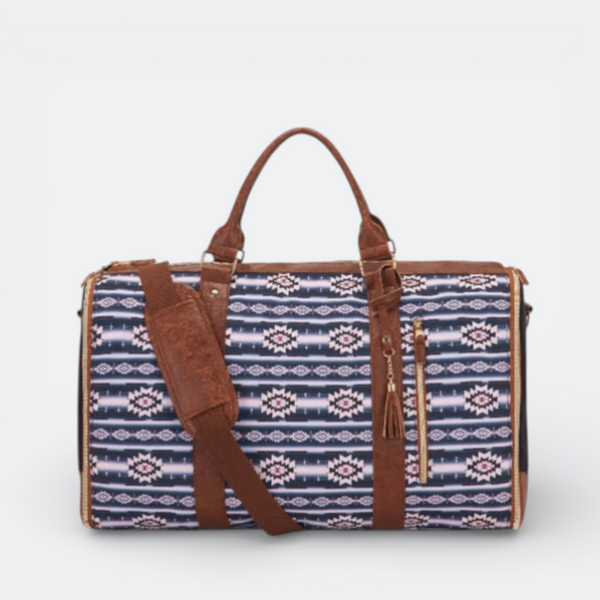AïtaVia expandable duffel bag with a navy, pink, and white geometric pattern and brown leather accents. Features top handles and a crossbody strap.