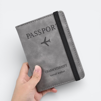AïtaVia grey faux leather passport holder with an elastic band and airplane motif. Text reads 'PASSPORT' and 'CHARMETERNITY travel wallet'.