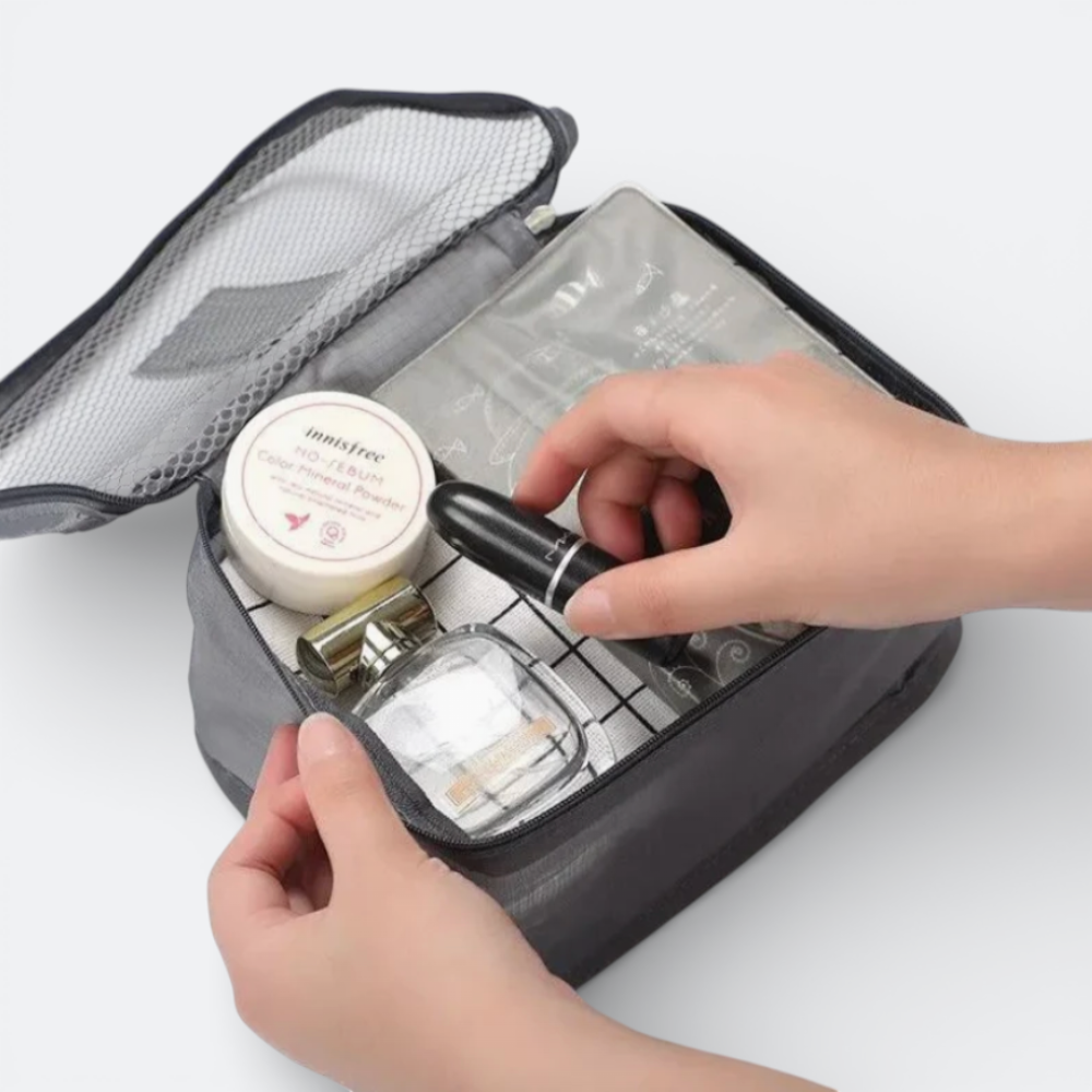 AïtaVia grey fabric travel organizer cube with mesh top, holding makeup and toiletries.