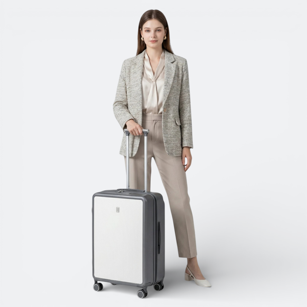 AïtaVia grey and white textured suitcase with a telescopic handle, held by a woman in a blazer and trousers.