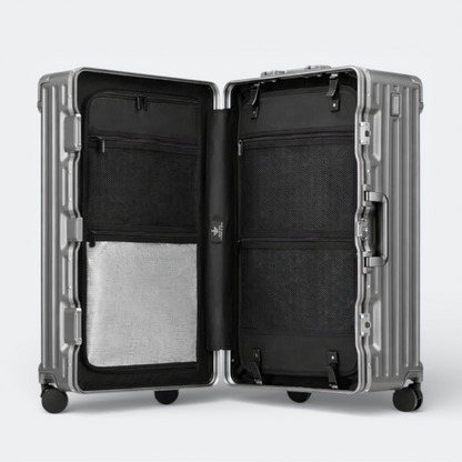 AïtaVia large silver hard-shell suitcase open, showing black interior with mesh pockets and straps.