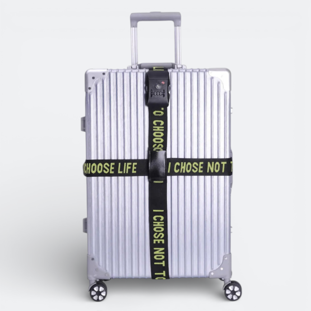 AïtaVia black luggage strap with combination lock and yellow text "CHOOSE LIFE I CHOSE NOT TO" securing a silver suitcase.