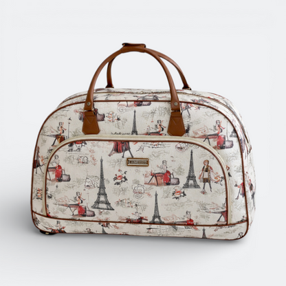 AïtaVia cream travel bag with a Parisian print featuring the Eiffel Tower and figures. Brown leather handles and trim.