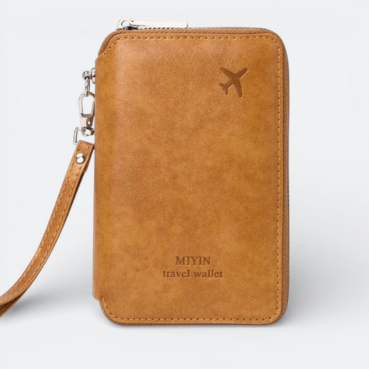 AïtaVia RFID passport holder in tan faux leather with airplane motif and wrist strap. Features zippered closure and embossed text.