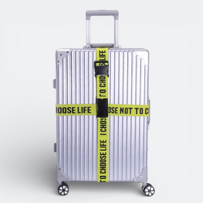 AïtaVia silver suitcase with yellow "TO CHOOSE LIFE" luggage straps and a code lock.